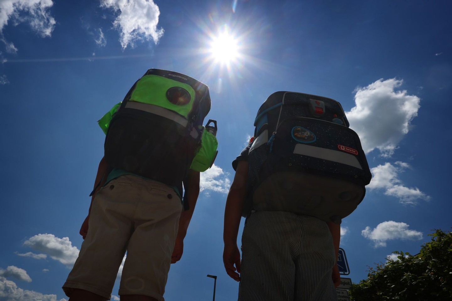 Zwei Kinder laufen mit ihren Schulranzen im Sonnenschein.